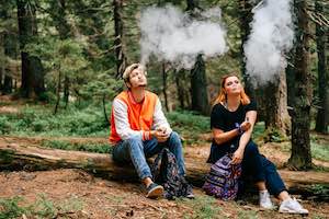 Ett par rökare som njuter av elektroniska cigaretter i bergsskogen
